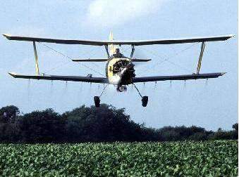 a farmer is using a crop duster to spray chemicals on his crops to kill in